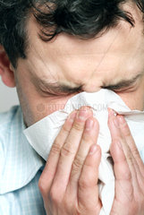Mann niest in ein Taschentuch