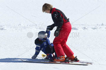 Ein Skilehrer hilft einem Kind beim Ski fahren