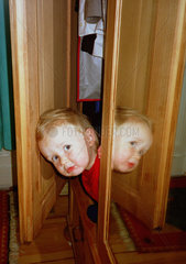 Kind beim Spielen im Schrank