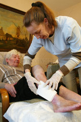 Eine Rentnerin wird von einer Altenpflegerin versorgt