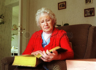 Eine alte Frau liest in einer Bibel.