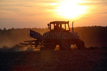 Prangendorf  Deutschland  Symbol Hitze  Traktor bei Sonnenuntergang auf dem Feld