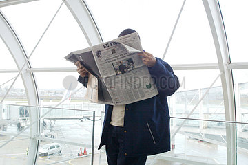 Paris  ein Wartender liesst Zeitung am Flughafen