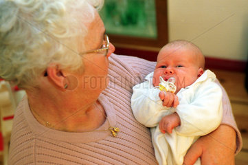 Eine Grossmutter hat ihre Enkelin auf dem Arm