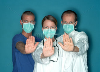 Gruppe von zwei Aerzten und OP Pfleger mit Mundschutz