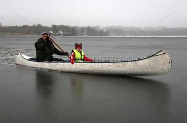 Belloe  Schweden  Mann und Kind sitzen in einem Kanu auf einem zugefrorenen See