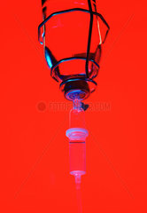 Infusionsflasche als Silhouette vor rotem Hintergrund