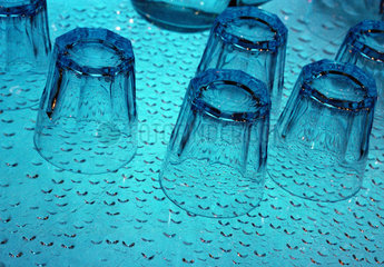Wasserglaeser stehen auf einer blau beleuchteten Flaeche