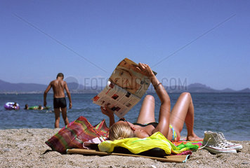 Eine junge Frau liest am Strand