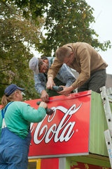 Poznan  Polen  Arbeiter befestigen Schild mit Coca-Cola-Reklame an einem Imbiss