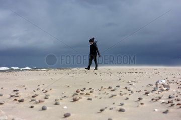 Kolberg  Polen  Frau laeuft bei Regenwetter allein am Strand entlang