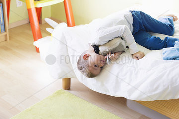 Boy lying on bed with stuffed toy