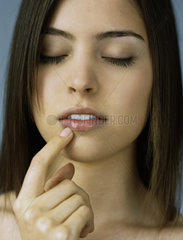 Teenage girl touching lip  eyes closed  portrait