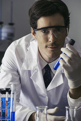 Scientist holding test tube in lab  looking at camera with determined expression