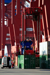 Hamburg  Deutschland  Hafenarbeiter und Portalhubwagen unter den Containerbruecken