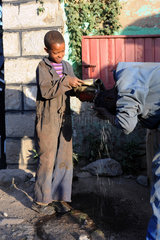 Mangudo  Aethiopien  ein Kind hilft einem Mann beim Waschen