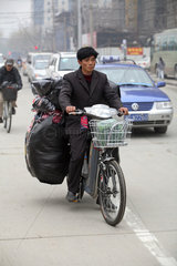 Shanghai  Mann faehrt ein voll beladenes Fahrrad