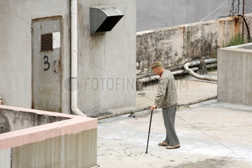 Hong Kong  alter Mann macht einen Spaziergang auf einem Hausdach