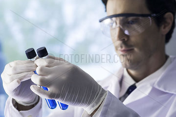 Scientist scrutinizing test tubes containing blue liquid in lab