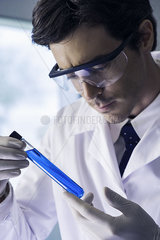 Chemist examing test tube containing blue liquid in laboratory