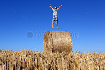 Torre Alfina  Italien  Junge springt auf einem Strohballen in die Luft