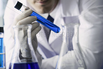 Chemist examining test tube containing blue liquid  cropped