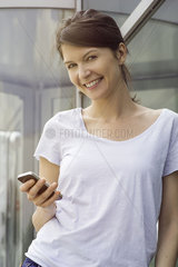 Woman using smartphone outdoors  smiling cheerfully
