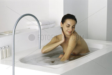 Woman sitting in bath  eyes closed