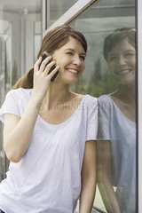 Woman leaning against window talking on cell phone