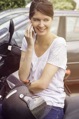 Woman sitting on parked motorcyle  talking on cell phone