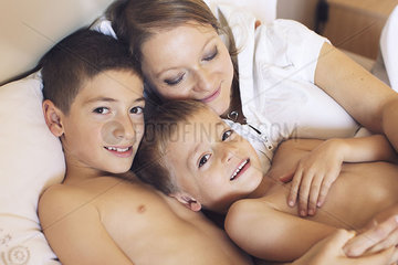 Mother and young sons relaxing together on bed  portrait