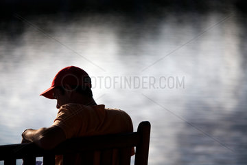 Vannes  Frankreich  ein junger Mann mit Basecap sitzt auf einer Bank am Meer