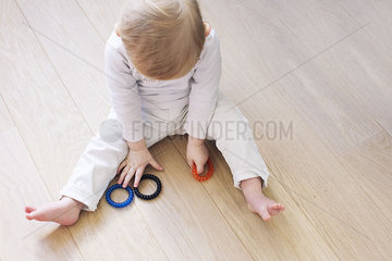 Baby sitting on floor playing with teething toys