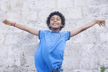 Boy standing with his arms outstretched  eyes closed  portrait