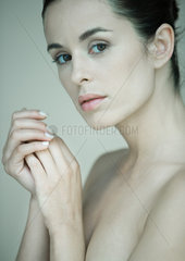 Woman with bare shoulders  hands clasped near face  portrait
