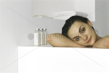 Woman resting head on side of bathtub  smiling  portrait