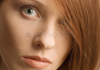 Woman's face and red hair covering one eye