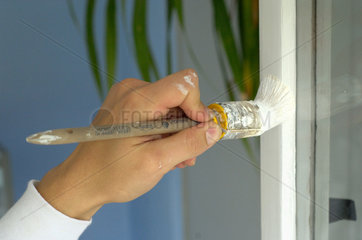 Berlin  Deutschland  Handwerker streicht den Rahmen eines Fensters