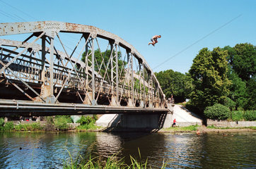 Jugendlicher springt zum Spass von einer Bruecke ins Wasser  Russland (Kaliningrad)