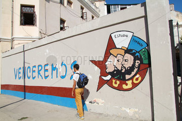 Havanna  Kuba  ein Schuljunge geht an einer Werbung der UJC vorbei