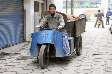 Suzhou  Mann faehrt ein mit Schutt beladenes motorisiertes Dreirad