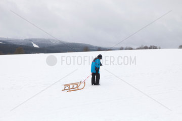 Winterberg  Deutschland  Junge mit Schlitten im winterlichen Sauerland