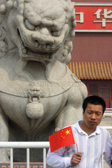 Peking  Mann mit China-Faehnchen vor dem Loewen