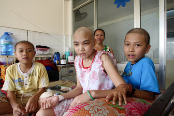 In einer Krebsstation eines Hospitals sitzen krebskranke Kinder auf einem Bett
