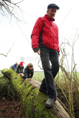 Prangendorf  Deutschland  Kinder krabbeln einem Mann auf einem Baumstamm hinterher