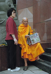 Eine Frau und ein aelterer buddhistischer Moench  Singapur