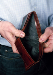 Ein Mann haelt einen leeren geoeffneten Geldbeutel