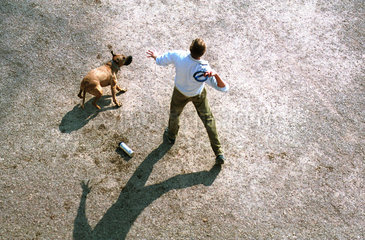 Ein junger Mann spielt mit seinem Hund.