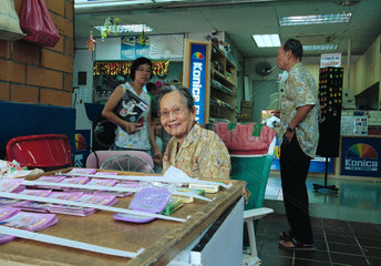 Eine alte Frau verkauft Lotterielose  Singapur