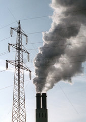 Rauchender Kraftwerksschornstein mit Strommast